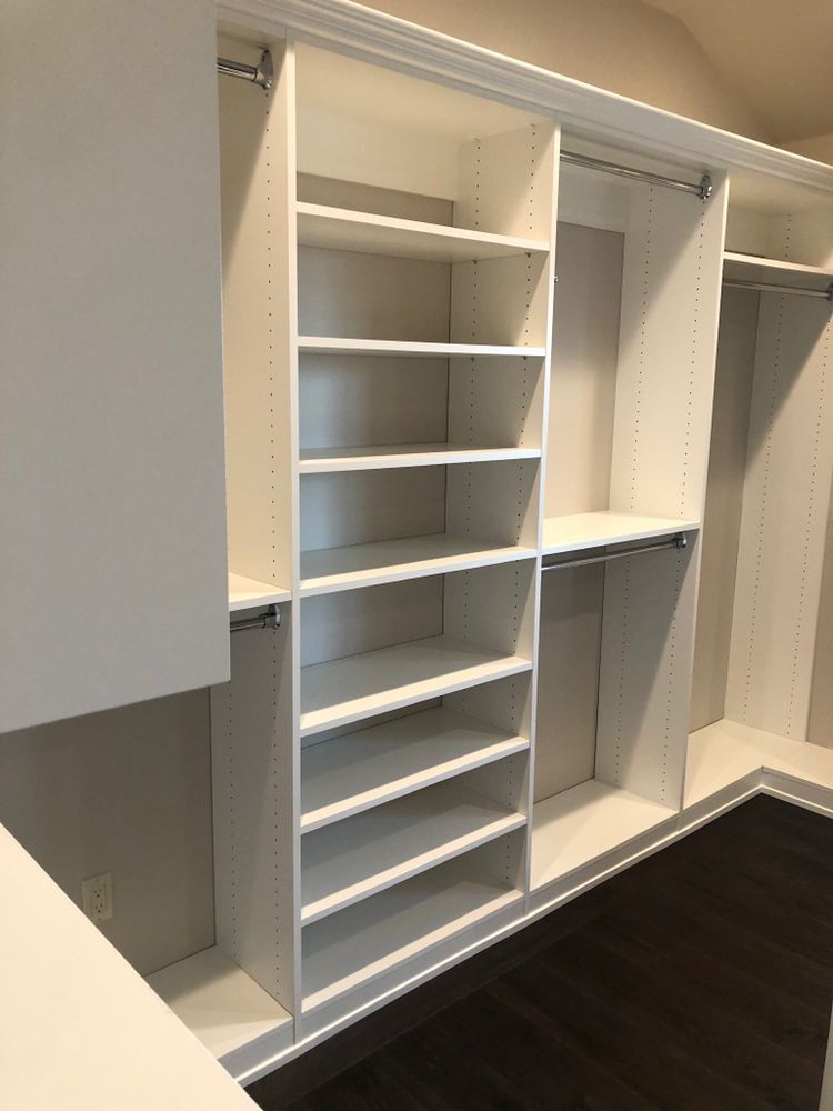 A walk in closet with lots of shelves and hanging clothes.