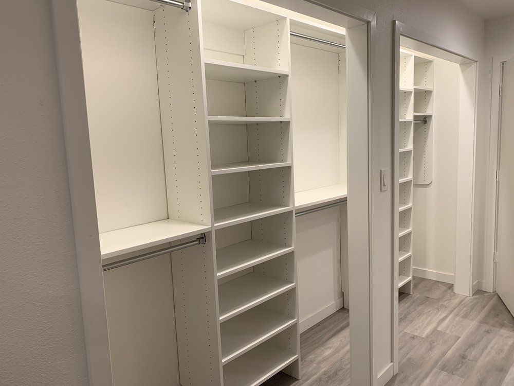 A walk in closet with lots of shelves and a mirror.