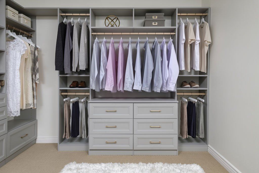 A walk in closet filled with lots of clothes and drawers.
