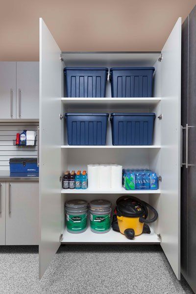 A garage cabinet filled with buckets , bins , and a vacuum cleaner.
