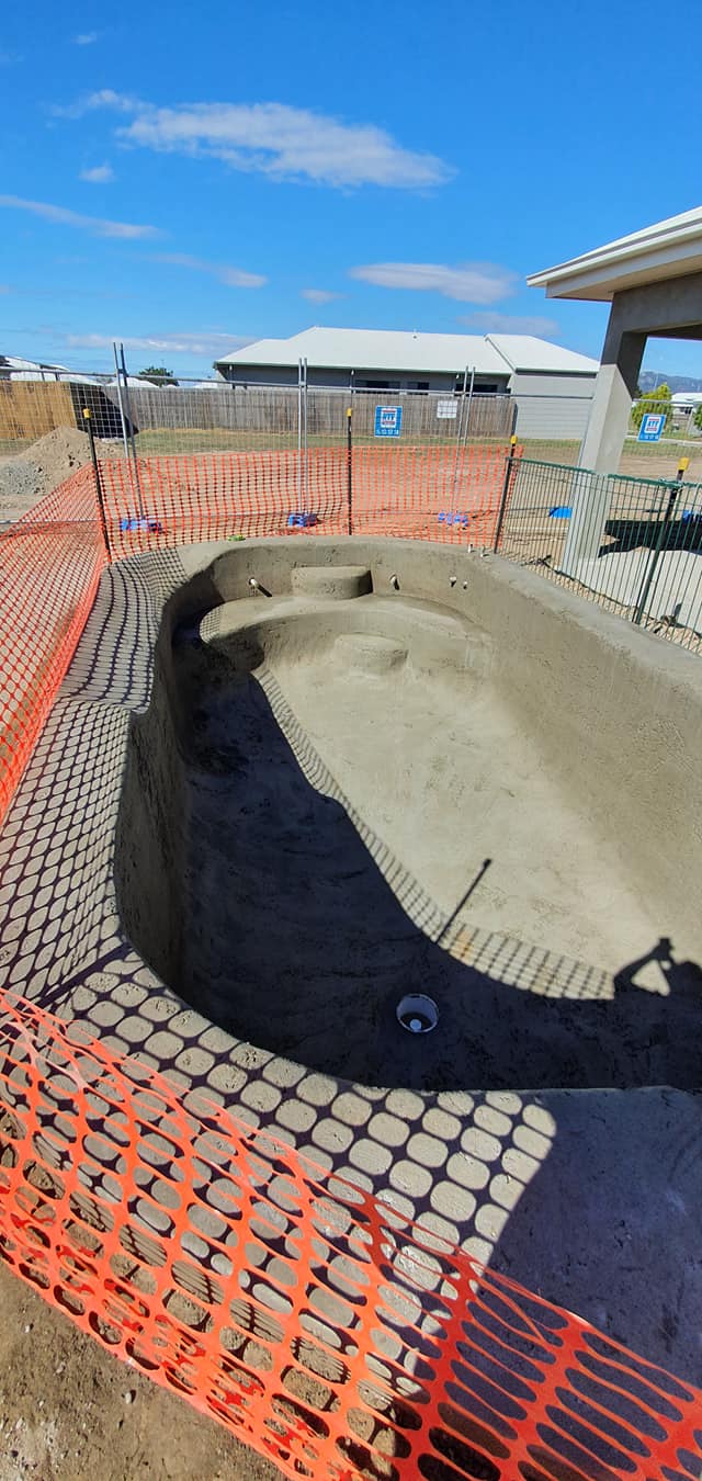 A Pool is Being Built in the Dirt With a Fence Around It — NQ Tropical Pools & Renovations in Cranbrook, QLD