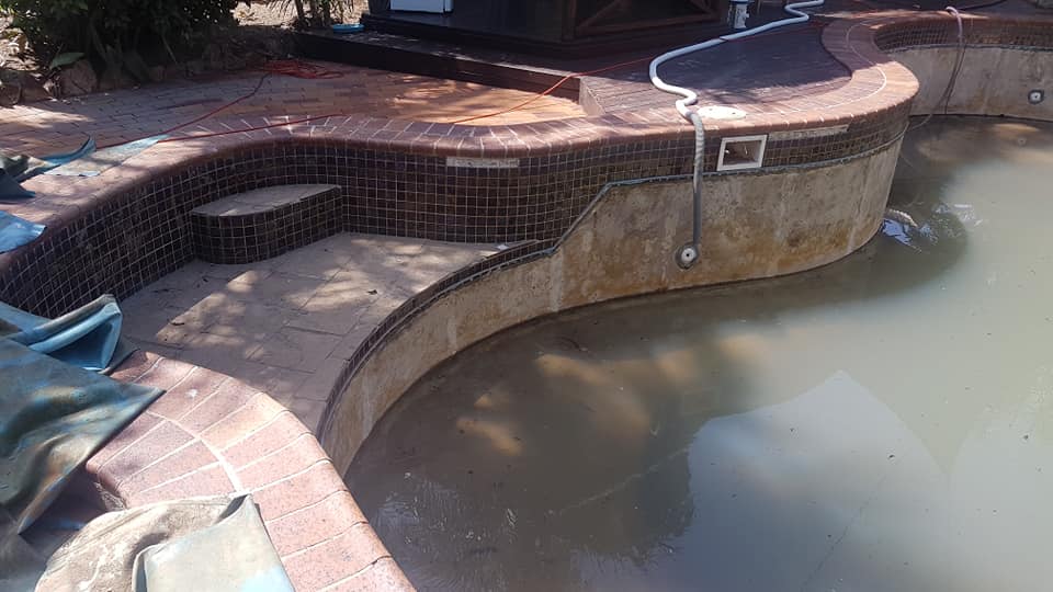 A Swimming Pool With a Hose Attached to the Side of It — NQ Tropical Pools & Renovations in Cranbrook, QLD
