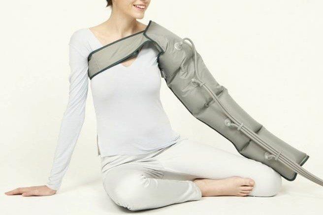 Eine Frau sitzt mit einem Gerät am Arm auf dem Boden