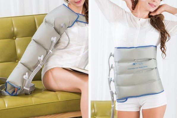 Eine Frau sitzt mit einer Kompressionsmanschette auf einer Couch