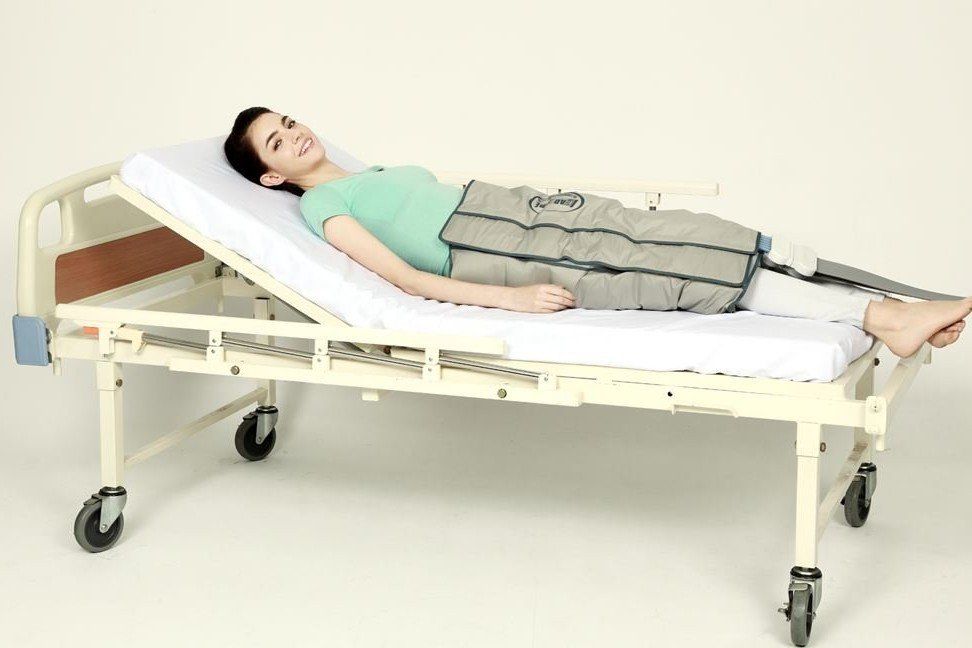 Eine Frau liegt mit einem Kompressionsverband in einem Krankenhausbett.