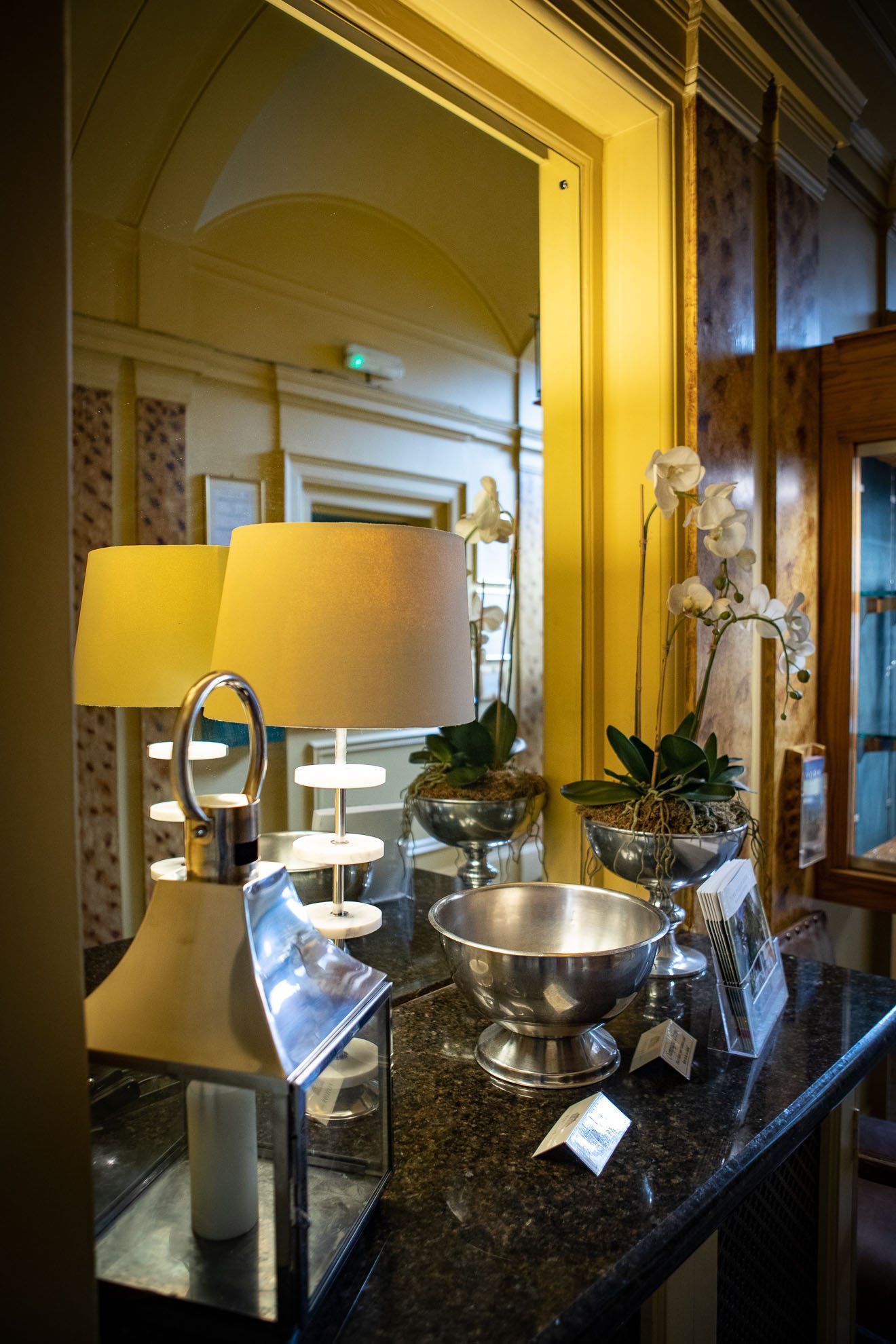 A table with lamps and vases on it in front of a mirror.