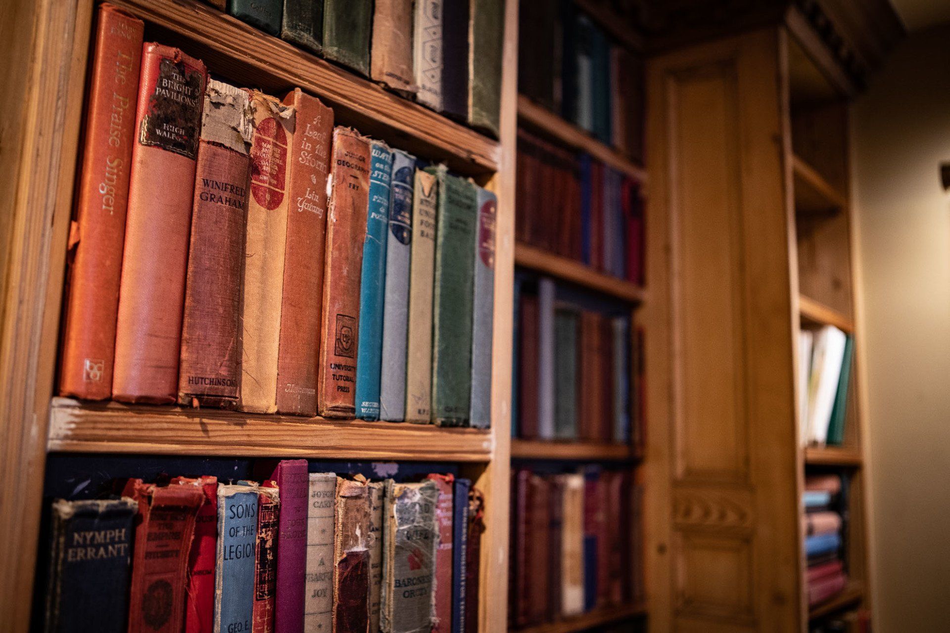 A library filled with lots of books on wooden shelves.