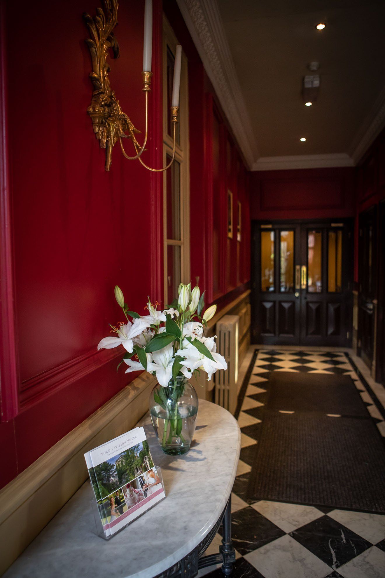 A vase of flowers is on a table in a hallway.