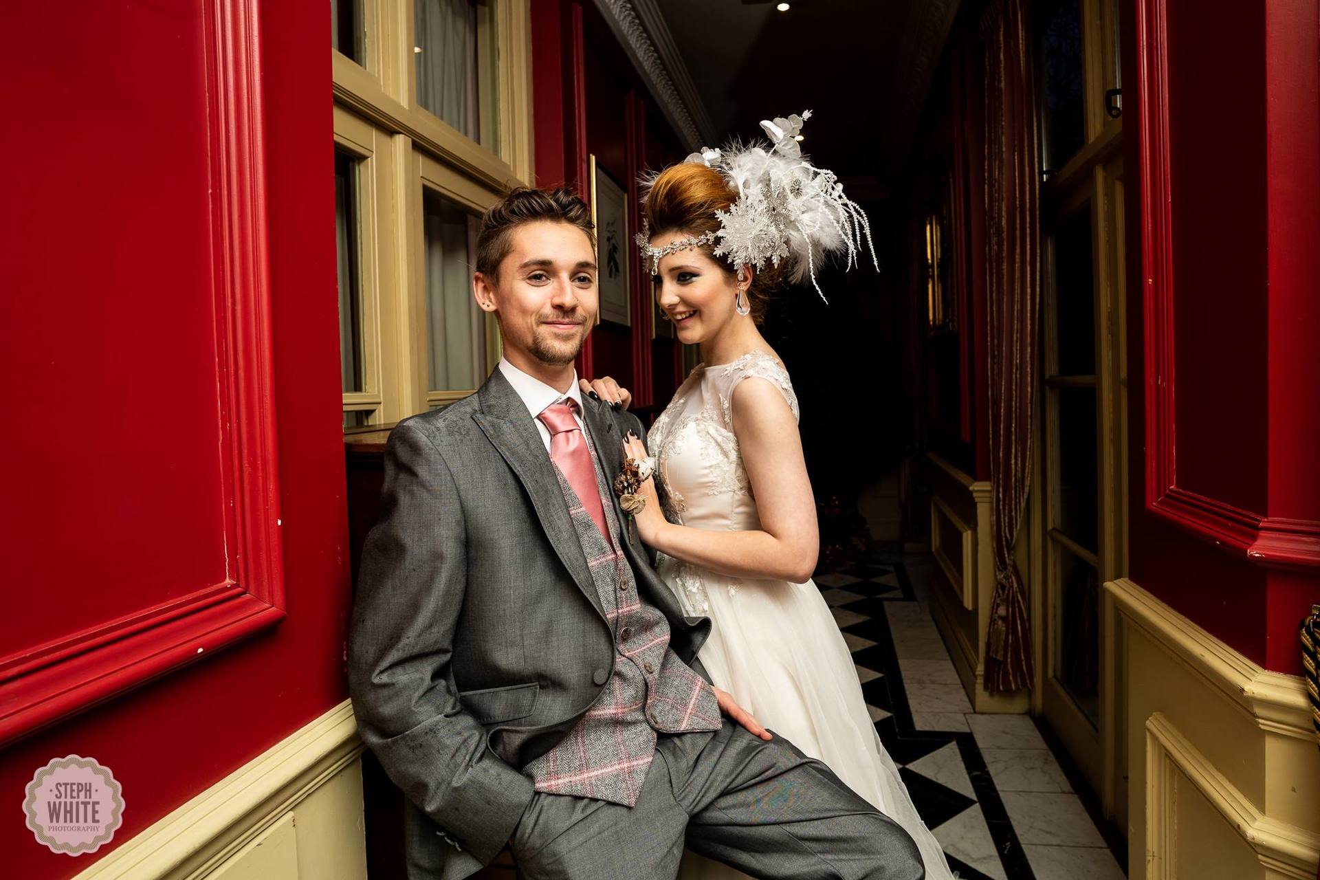 A bride and groom are posing for a picture in a hallway.