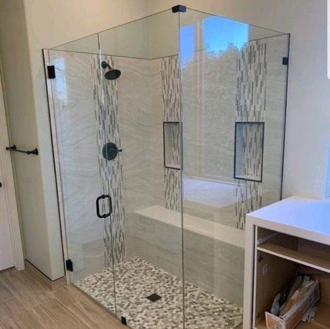 A bathroom with a walk in shower with a glass door.