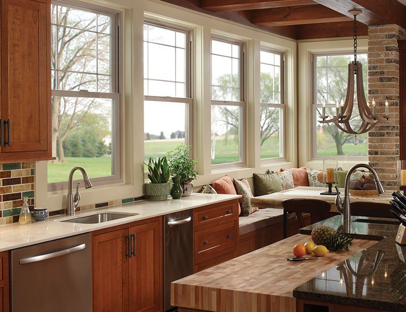 A kitchen with wooden cabinets , stainless steel appliances , a sink , and a large island.
