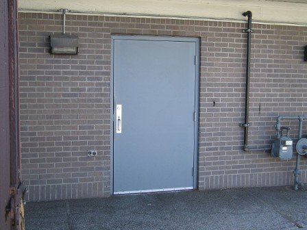 A gray door on a brick wall with a white handle
