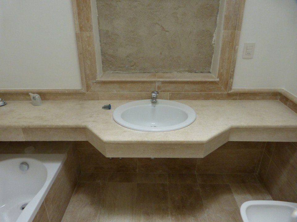 un lavabo in ceramica bianco incastonato in marmo beige