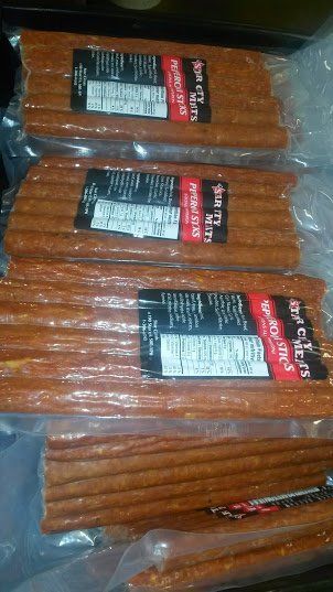 Several vacuum-sealed packages of thin, brown meat snack sticks stacked on top of each other.