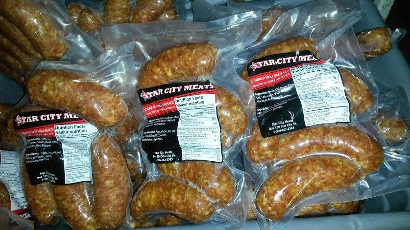 Multiple vacuum-sealed packages of Star City Meats sausages stacked together in a storage bin.