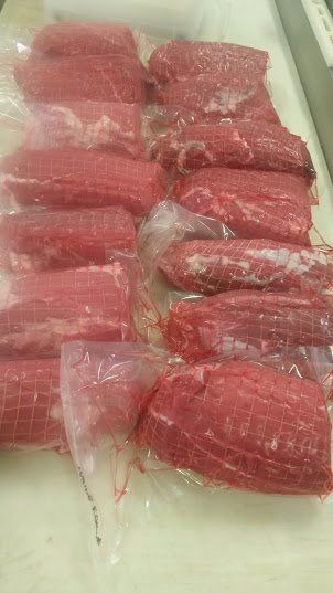 Several raw, red meat portions individually vacuum-sealed in clear plastic packaging arranged on a light surface.