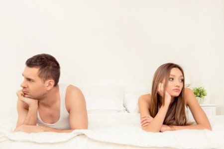 Coppia a letto con sguardi rivolti altrove