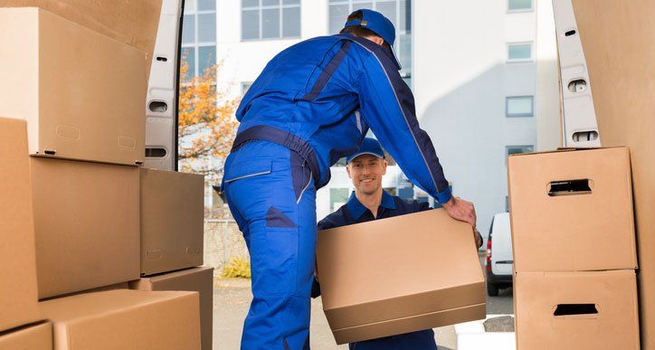 Movers Carrying Sofa Outside Truck On Street