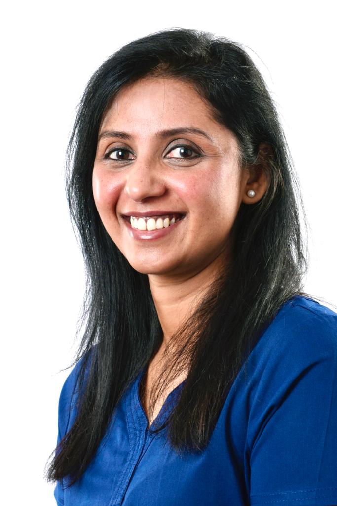 A woman in a blue shirt is smiling for the camera.