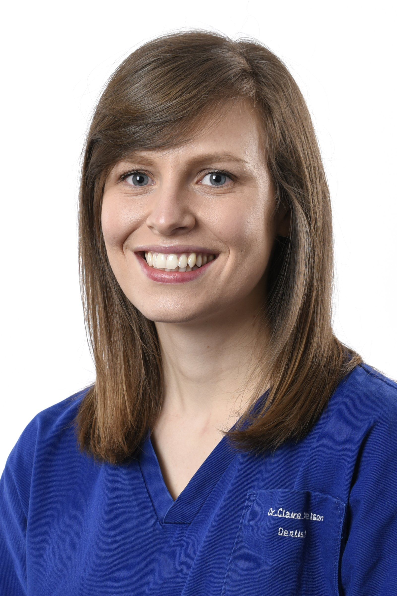 A woman in a blue scrub top is smiling for the camera.