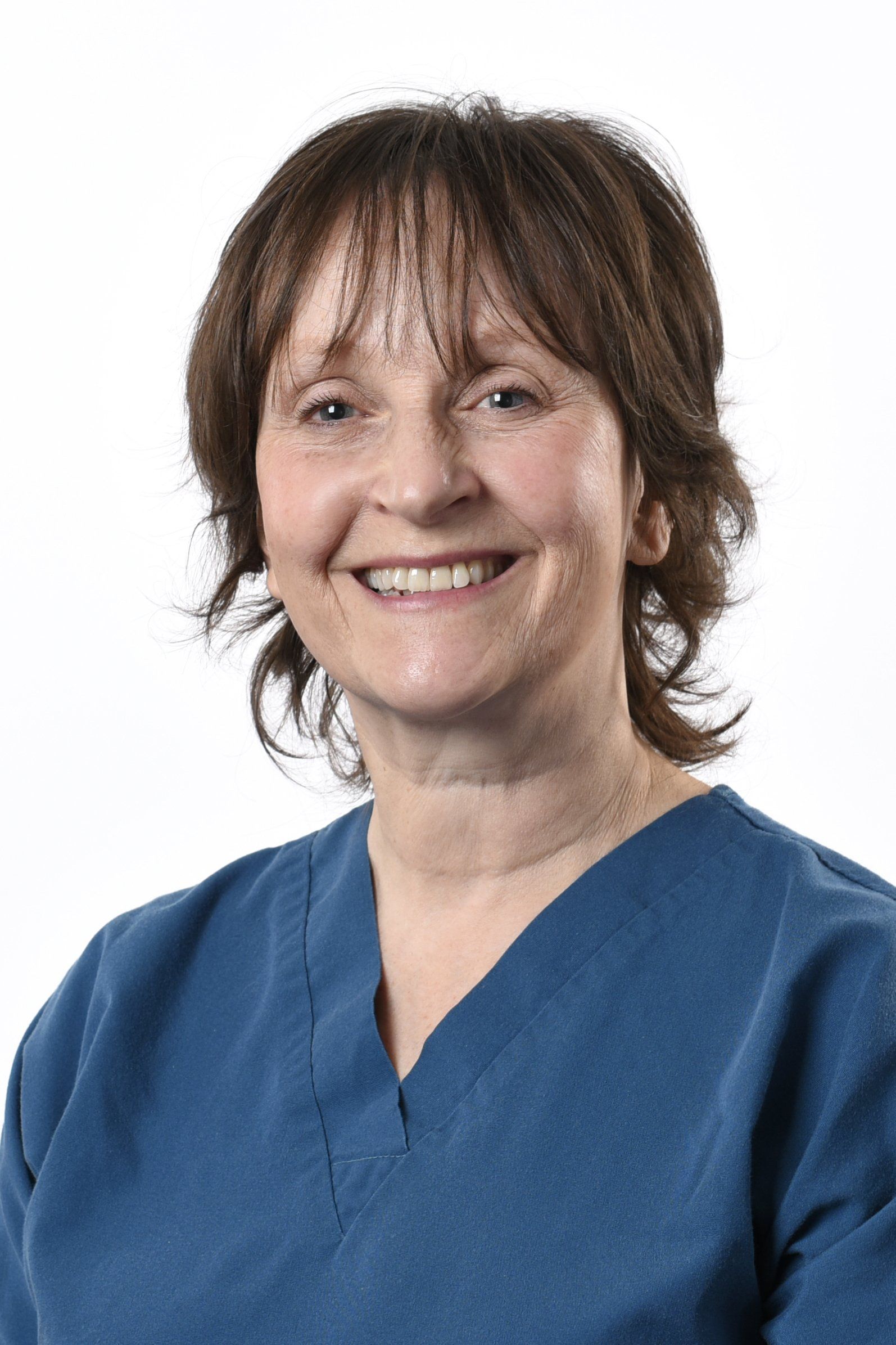 A woman in a blue scrub top is smiling for the camera.