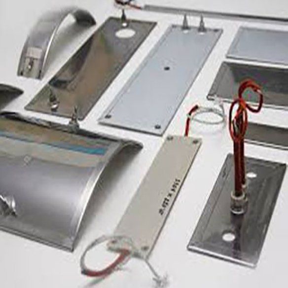 Diversos componentes metálicos y electrónicos dispuestos sobre una superficie blanca, cables y una sonda roja.