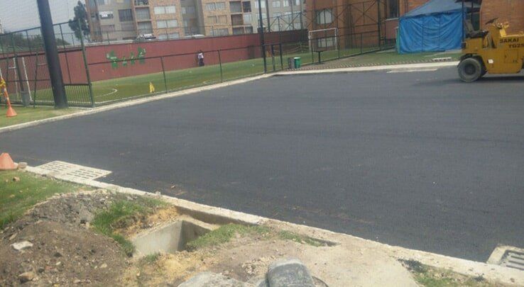 Asfalto recién pavimentado junto a una zona vallada