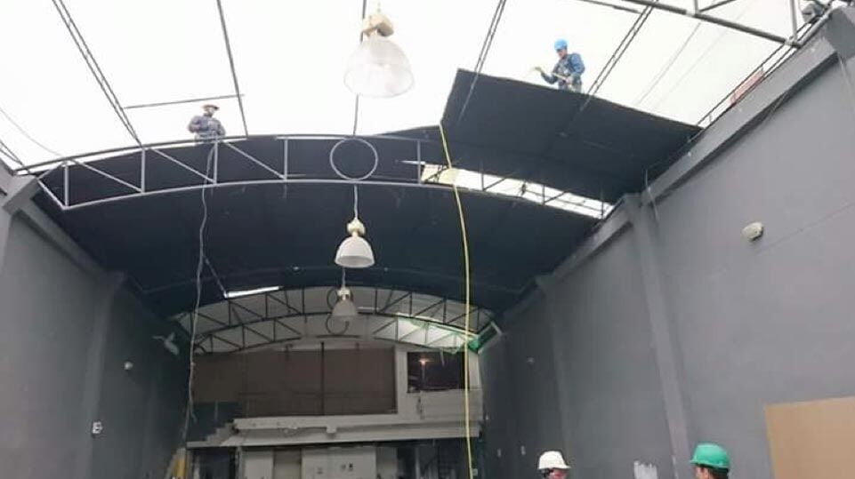 Interior de una obra en construcción de color gris, con techo parcialmente cubierto