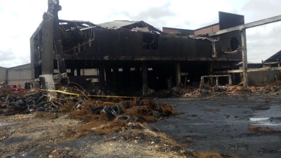 Almacén calcinado tras un incendio, con el techo derrumbado y escombros esparcidos por todo el terreno.