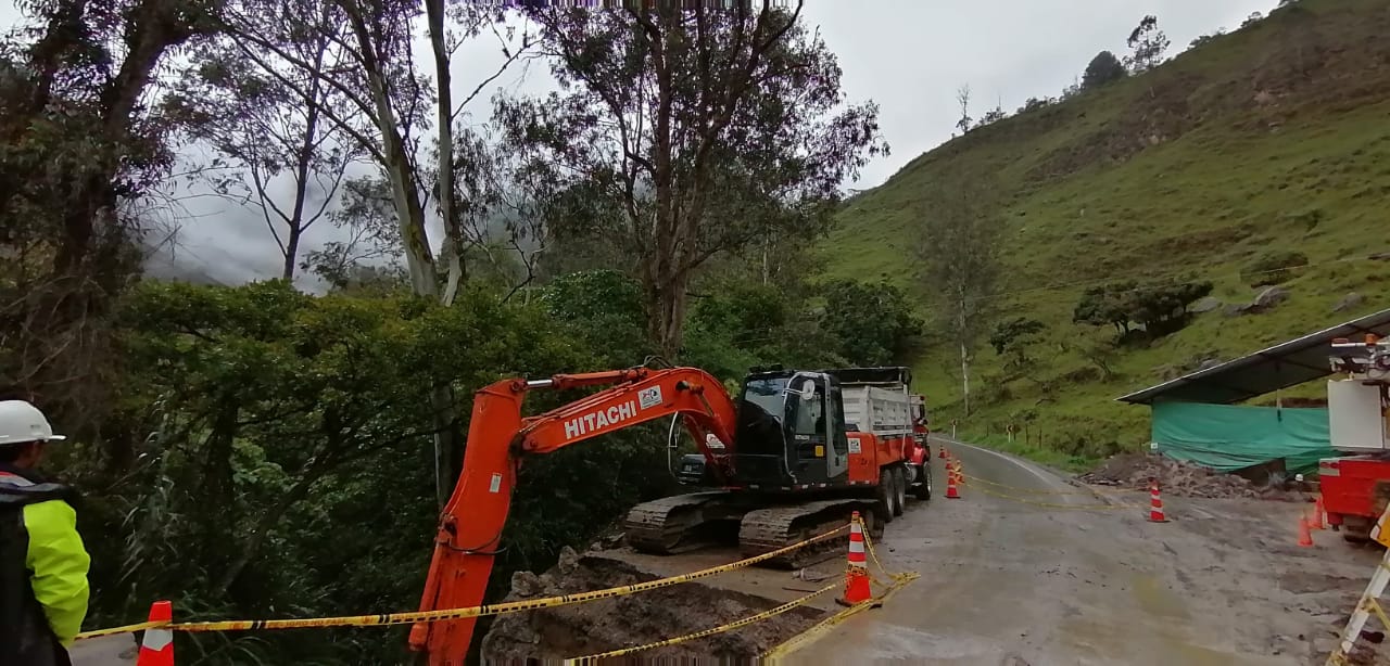 Excavadora naranja y trabajadores en un arcén embarrado