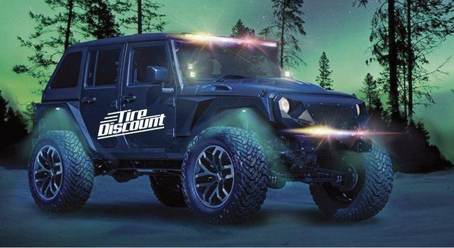 a black jeep is parked in front of a forest at night .