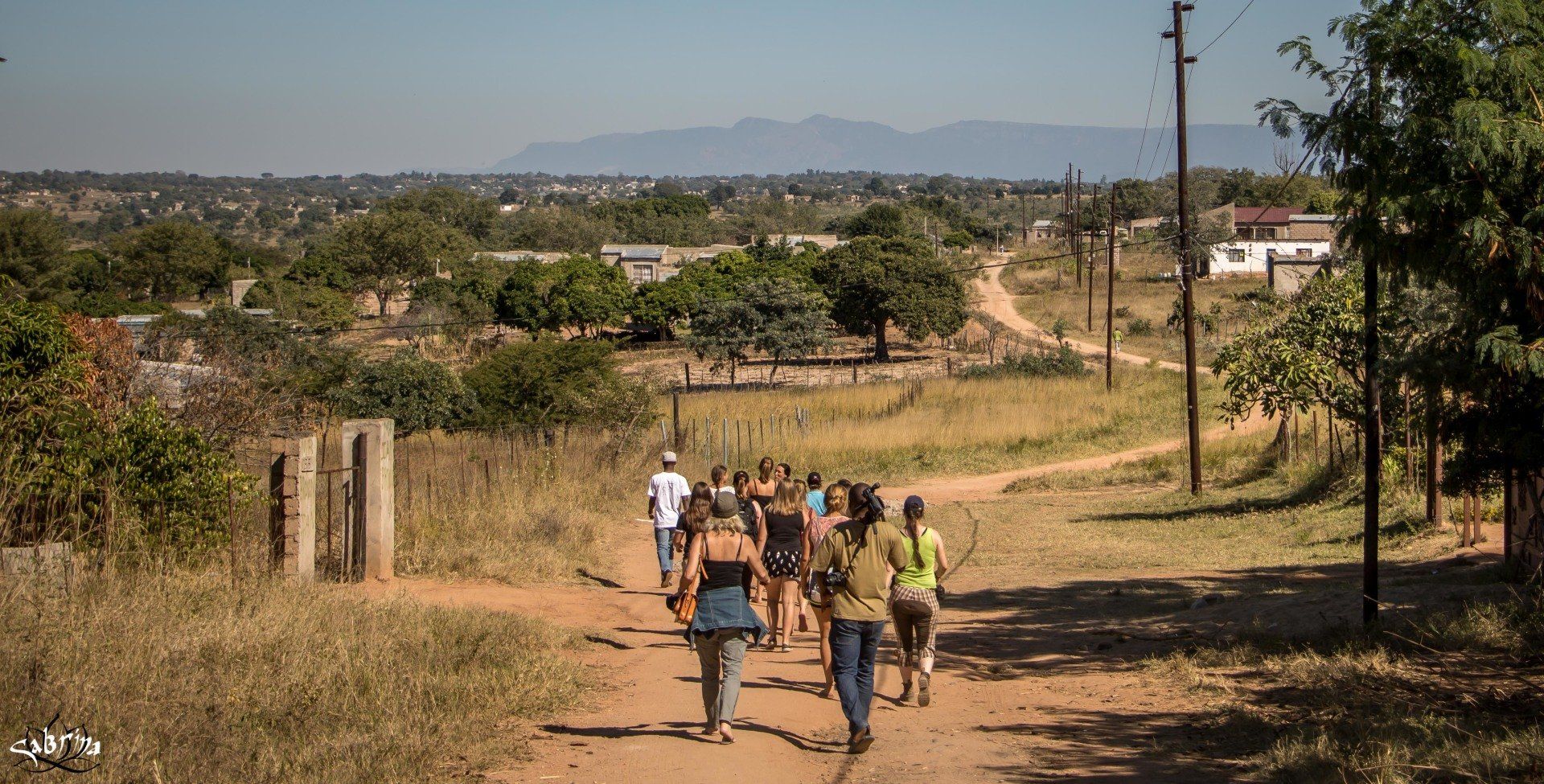 A group of people are walking down a dirt road.
