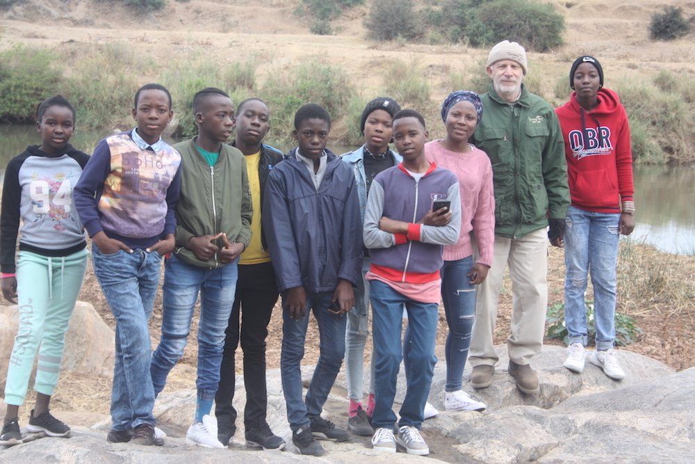 a group of people standing next to each other in front of a body of water .