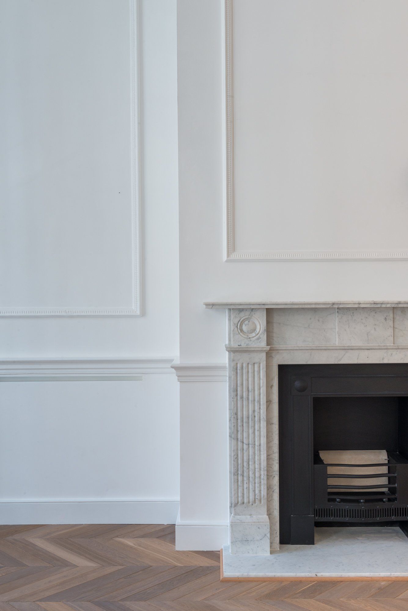 A fireplace in an empty room with white walls