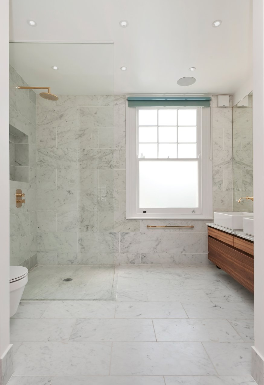 A bathroom with marble tiles and a walk in shower