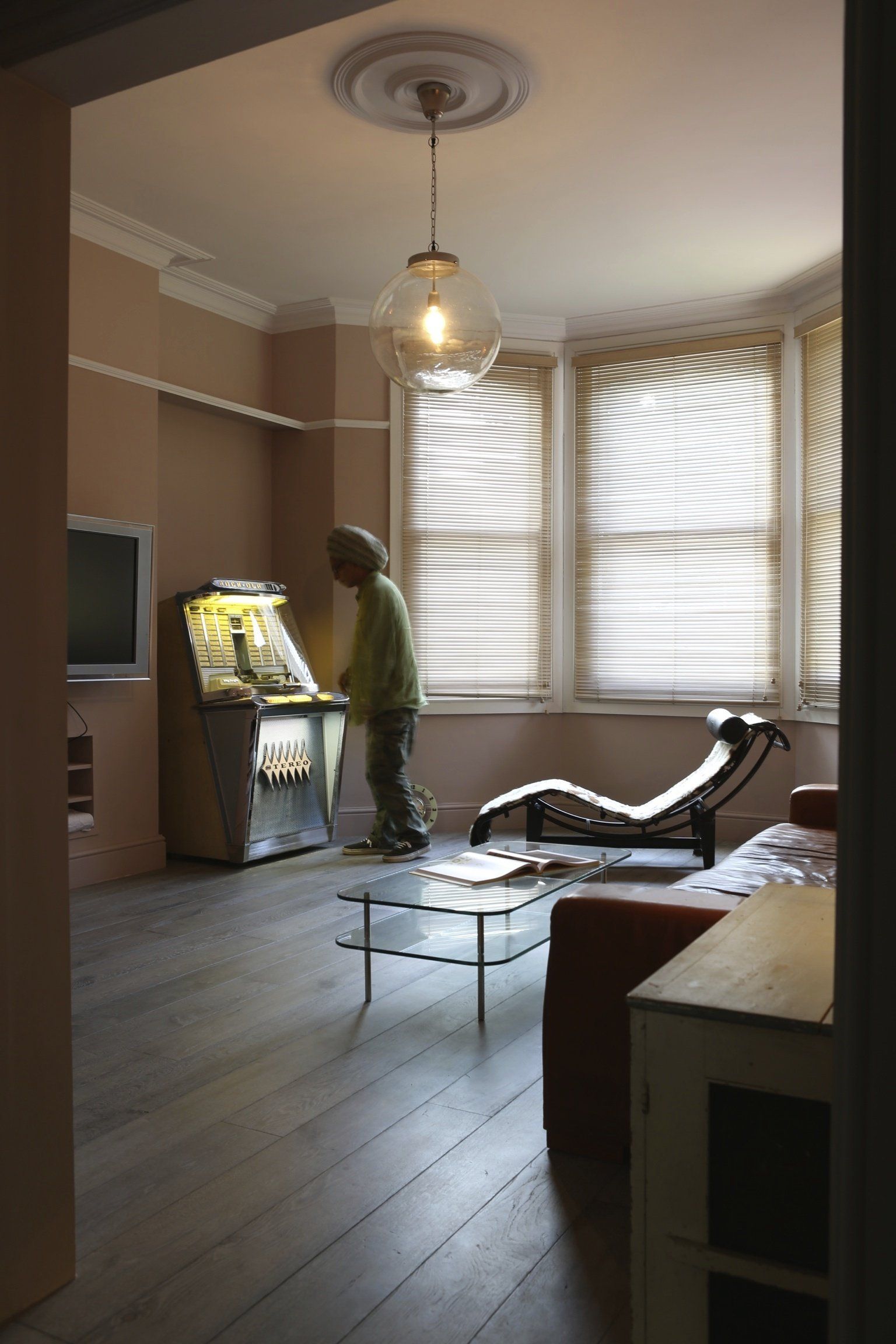 A man standing in a living room next to an arcade machine