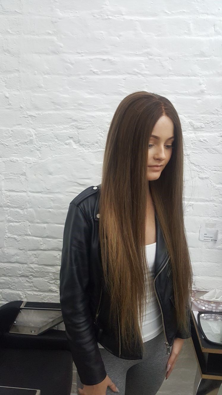 A candid, side profile photo of a woman with a long, brown hair wig