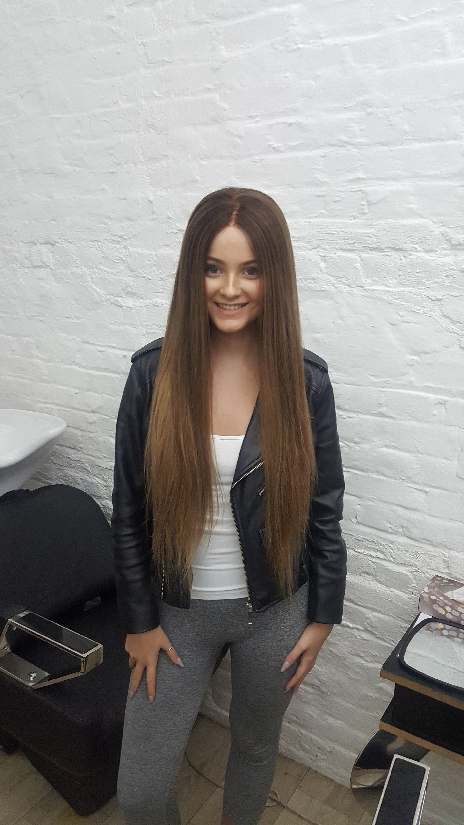 A smiling woman posing with a long, brown hair wig