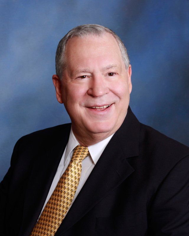 A man in a suit and tie is smiling for the camera