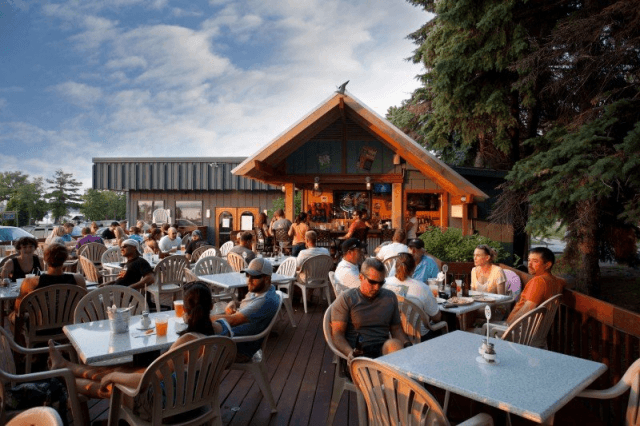 A group of people are sitting at tables outside of a restaurant.
