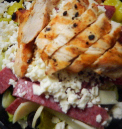 A close up of a salad with chicken and cheese