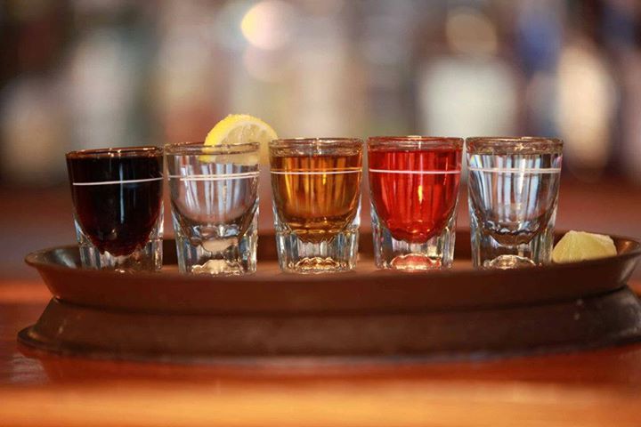 A tray of shot glasses filled with different types of alcohol.