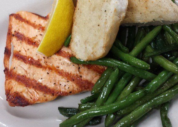A close up of a plate of food with green beans and salmon