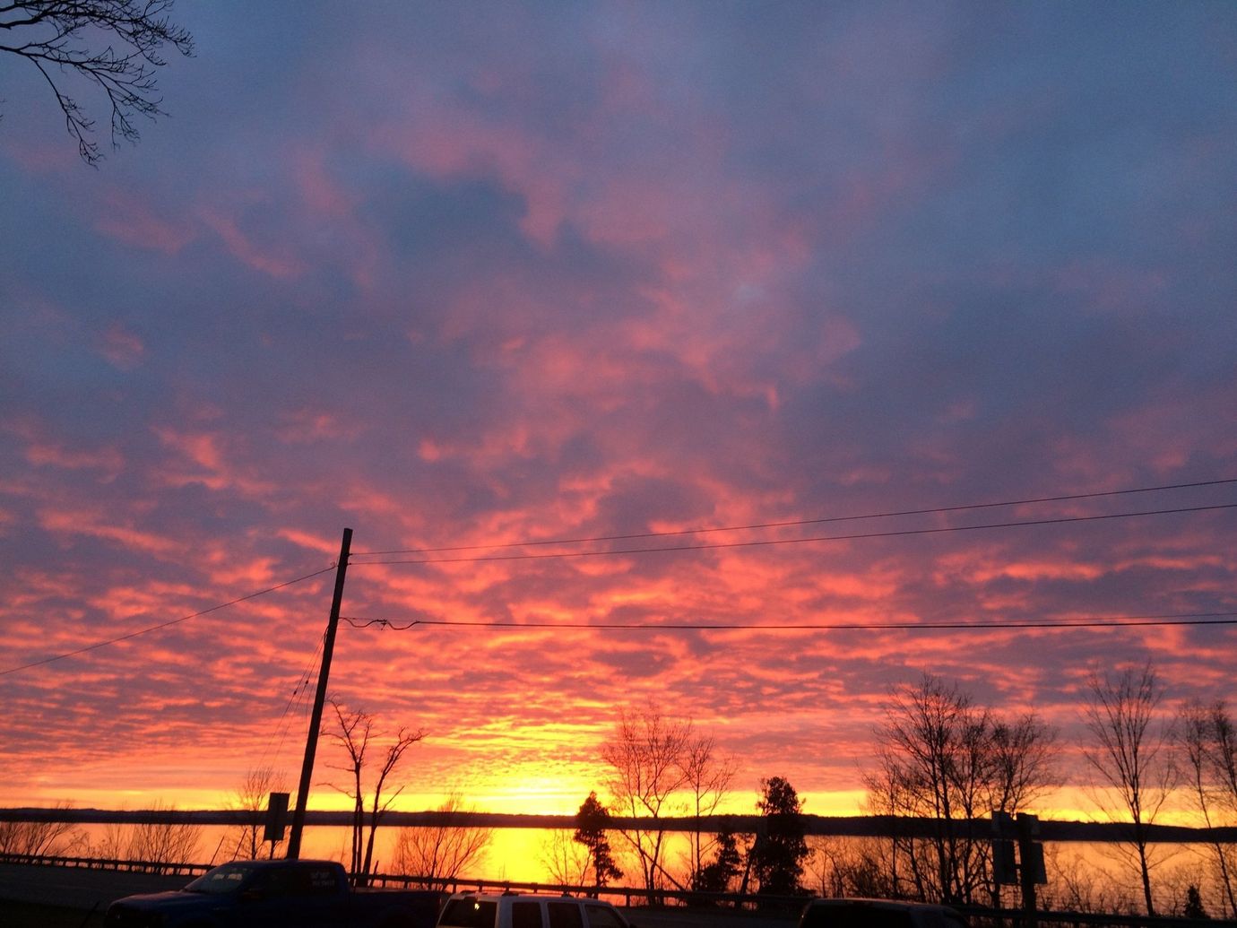 A sunset with a fence in the foreground and trees in the background