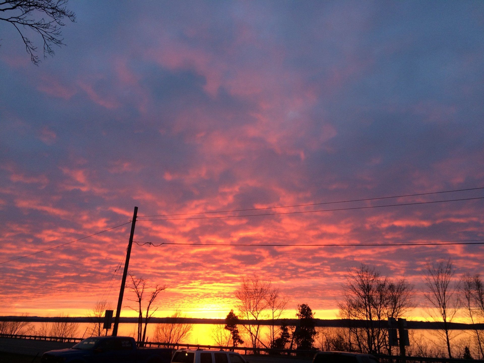 A sunset with a fence in the foreground and trees in the background