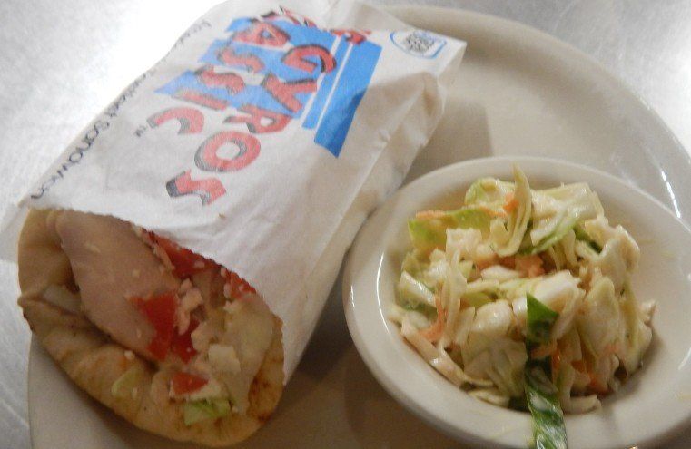 A bag of gyros and a bowl of coleslaw on a plate