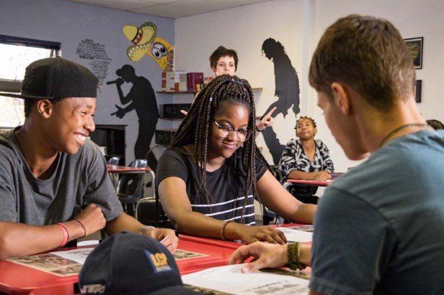 A group of young people are sitting around a table playing a game.