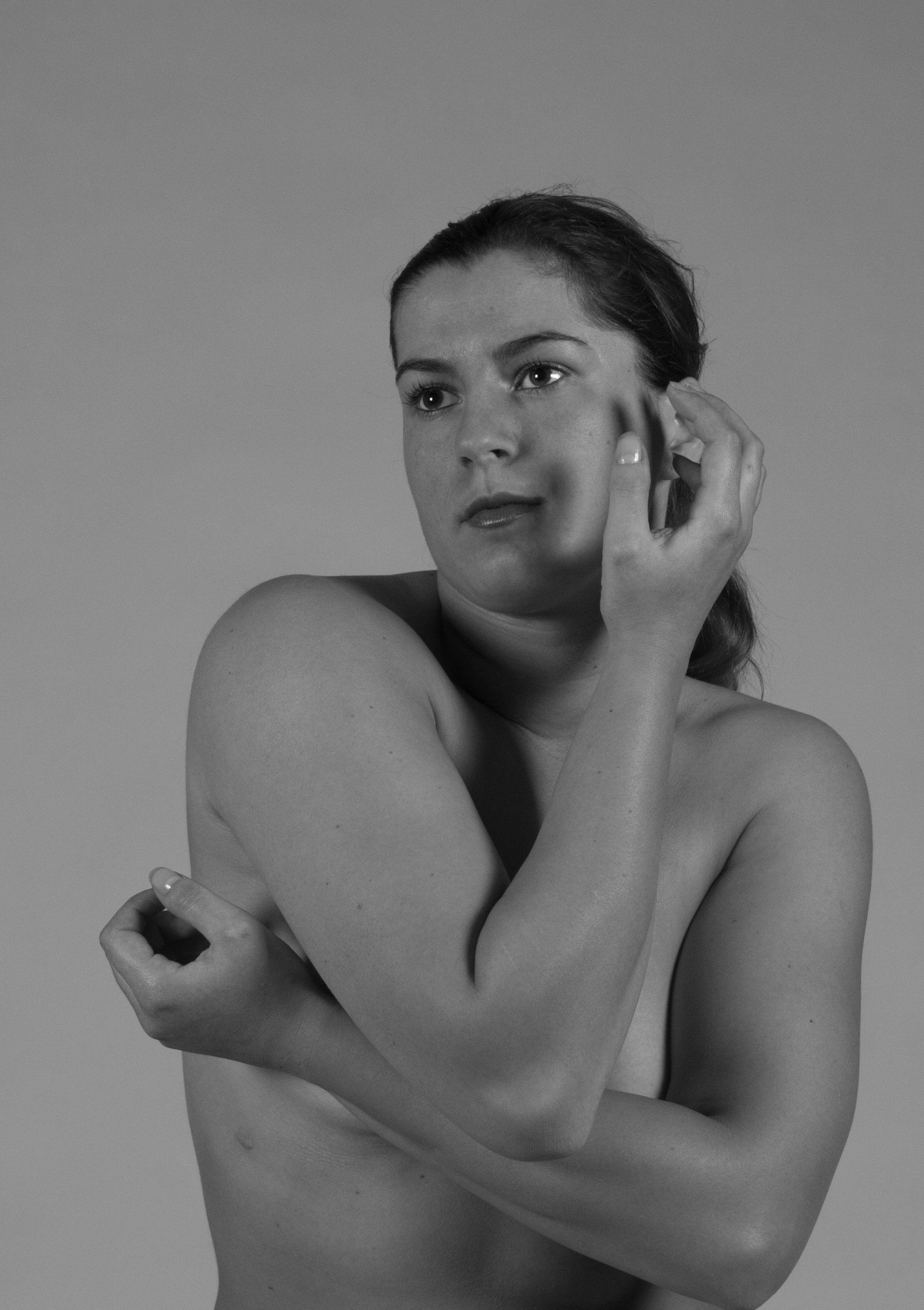 Zwart-wit portret van een persoon die poseert met één hand bij het gezicht en de andere hand over de borst.