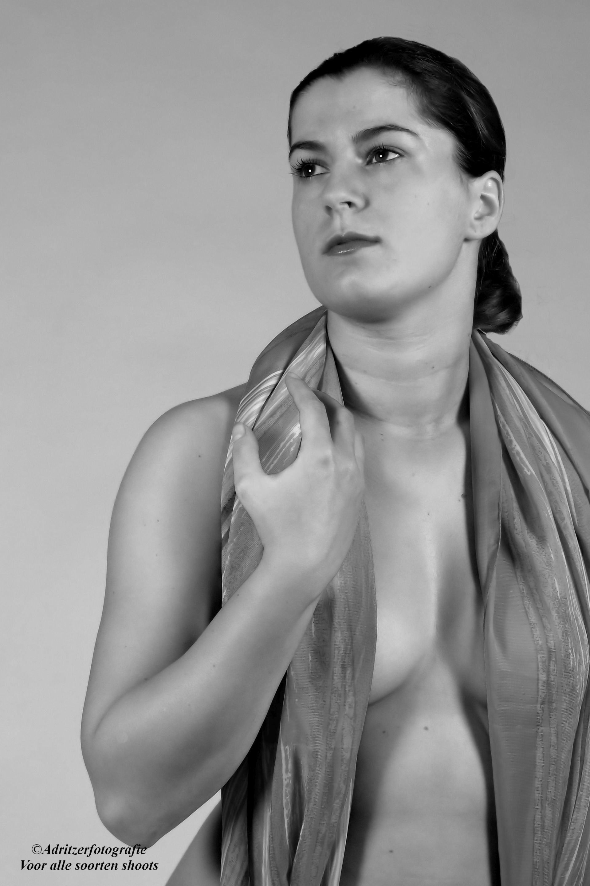 Zwart-witportret van een vrouw met een sjaal over één schouder, die opzij kijkt.