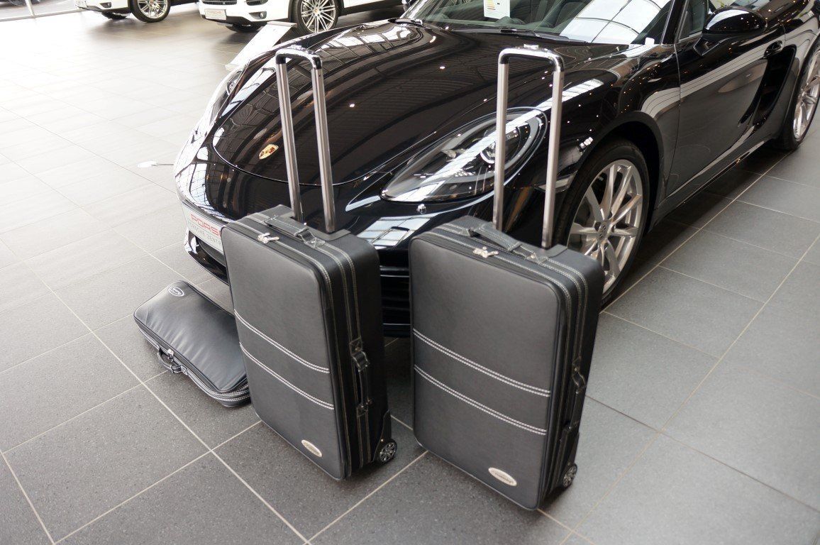 Twee koffers staan ​​voor een zwarte auto